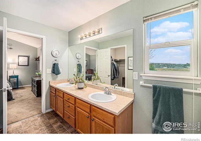 full bathroom with double vanity, baseboards, and a sink