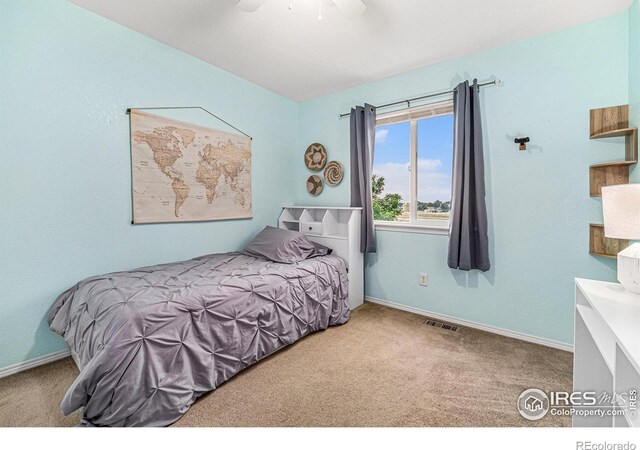 carpeted bedroom featuring a ceiling fan, visible vents, and baseboards