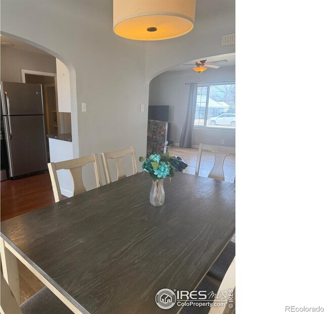 dining room featuring arched walkways, visible vents, a ceiling fan, and wood finished floors