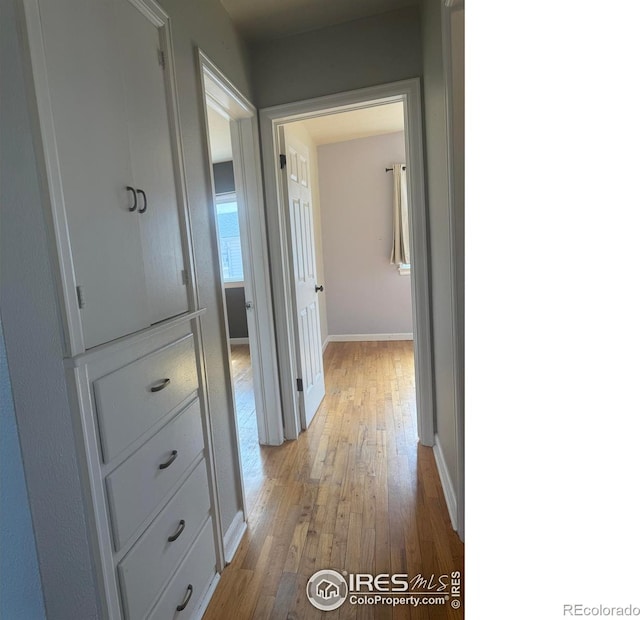 hall featuring light wood-style floors and baseboards