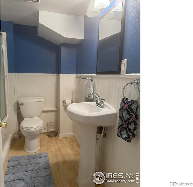 bathroom with toilet, wood finished floors, visible vents, and wainscoting