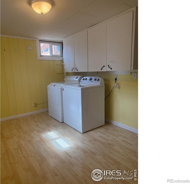 washroom featuring separate washer and dryer, cabinet space, light wood-type flooring, and baseboards