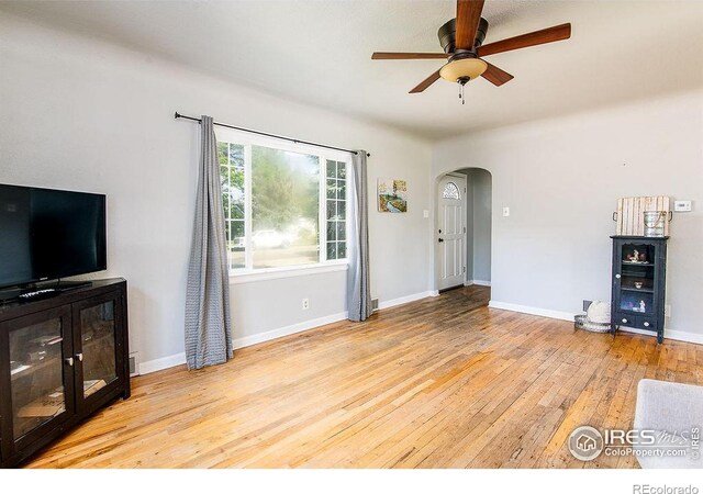 410 Cottonwood Ave, Eaton, CO 80615 - unfurnished living room with arched walkways, ceiling fan, light wood-type flooring, and baseboards