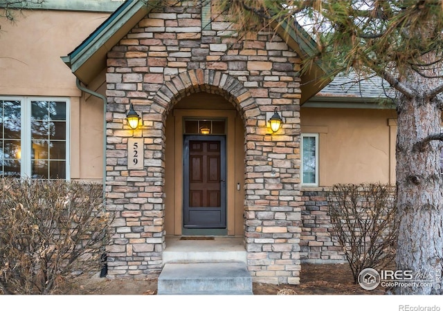 view of exterior entry with stone siding and stucco siding