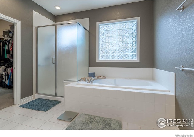 bathroom featuring a stall shower, tile patterned flooring, a spacious closet, and a garden tub