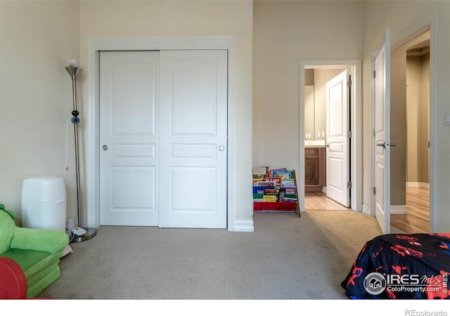 bedroom featuring a closet, carpet flooring, baseboards, and ensuite bathroom