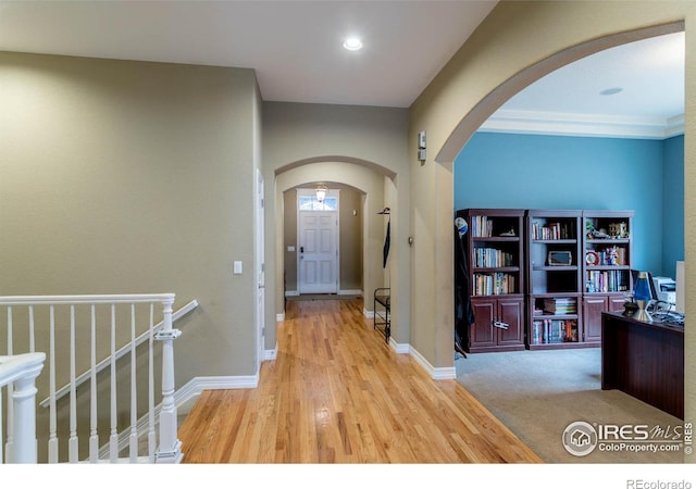 entryway featuring arched walkways, baseboards, and wood finished floors