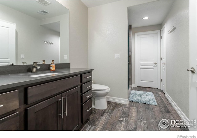 bathroom with baseboards, visible vents, toilet, wood finished floors, and vanity