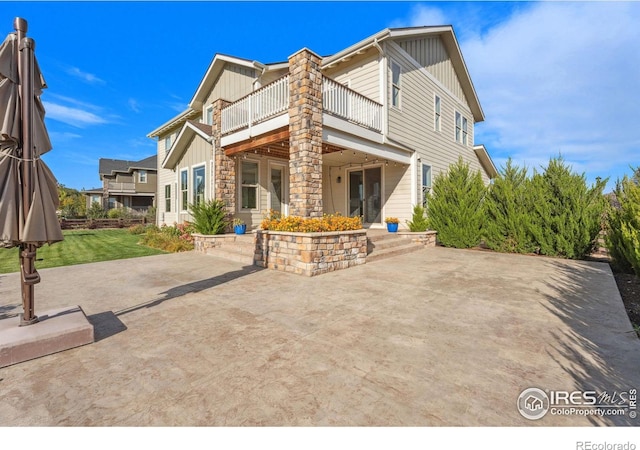 rear view of property featuring board and batten siding, a yard, and a patio