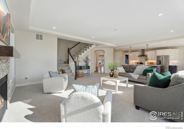 living room with visible vents, stairway, arched walkways, a fireplace, and light colored carpet