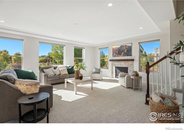 carpeted living room with stairway, plenty of natural light, and a glass covered fireplace