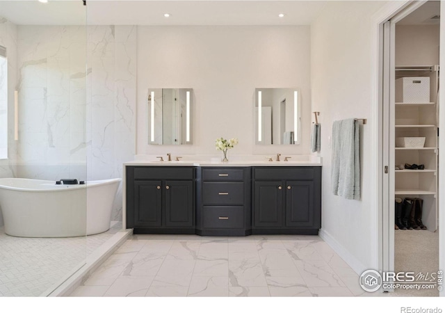 bathroom with double vanity, recessed lighting, marble finish floor, and a freestanding bath