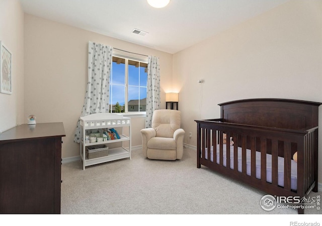 carpeted bedroom featuring visible vents, a crib, and baseboards