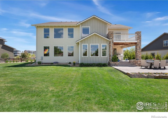 back of property featuring a patio, a balcony, a lawn, and board and batten siding