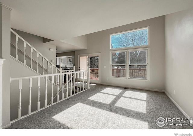 carpeted spare room featuring stairway and baseboards