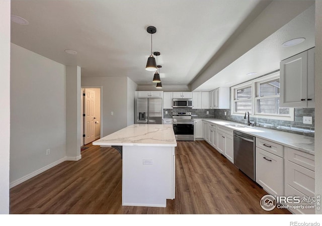 kitchen featuring tasteful backsplash, dark wood-style floors, a kitchen island, appliances with stainless steel finishes, and a sink