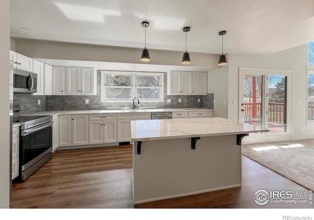 kitchen featuring white cabinets, decorative backsplash, stainless steel appliances, a kitchen bar, and a sink