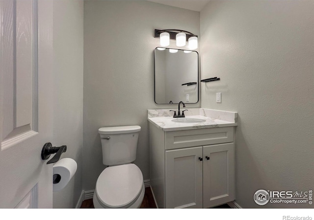 bathroom featuring baseboards, vanity, and toilet