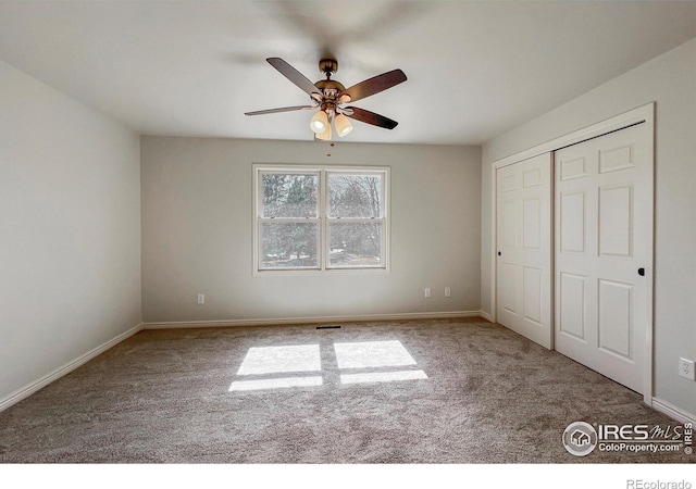 unfurnished bedroom featuring carpet, baseboards, ceiling fan, and a closet