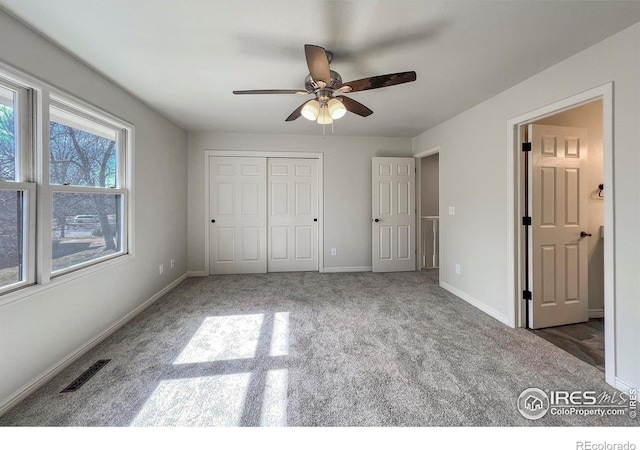 unfurnished bedroom featuring a ceiling fan, visible vents, baseboards, a closet, and carpet