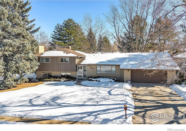 split level home featuring a garage, driveway, and a chimney