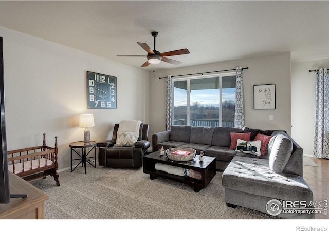 carpeted living room with ceiling fan and baseboards