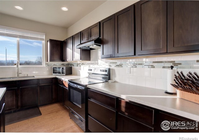 kitchen with electric stove, light wood-style floors, a sink, dark brown cabinetry, and under cabinet range hood