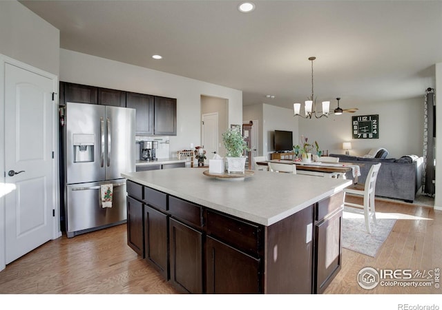 kitchen with a center island, light wood-style flooring, open floor plan, dark brown cabinetry, and stainless steel fridge with ice dispenser