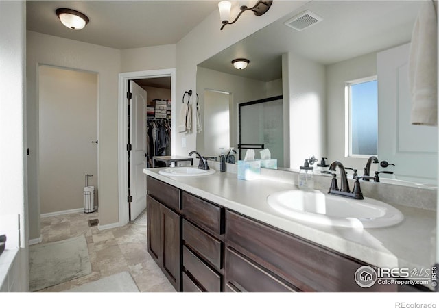 bathroom with a stall shower, a sink, visible vents, and a walk in closet