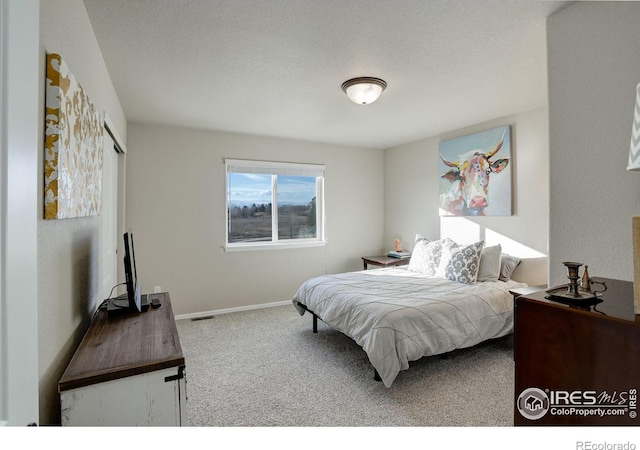 carpeted bedroom with visible vents, a textured ceiling, and baseboards