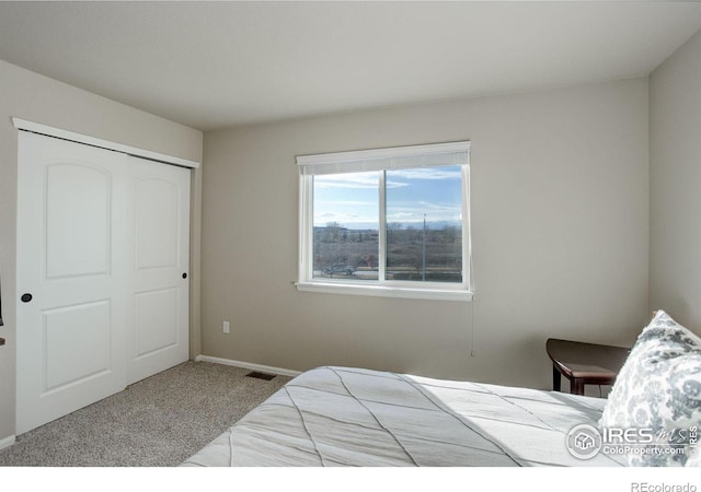 carpeted bedroom featuring a closet, visible vents, and baseboards