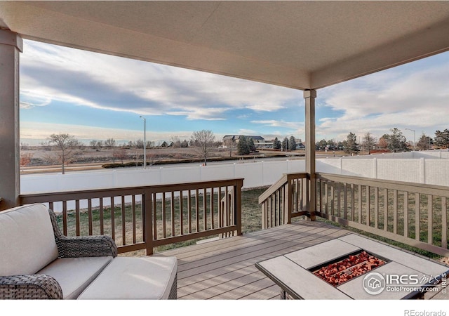 wooden deck with an outdoor fire pit and a fenced backyard