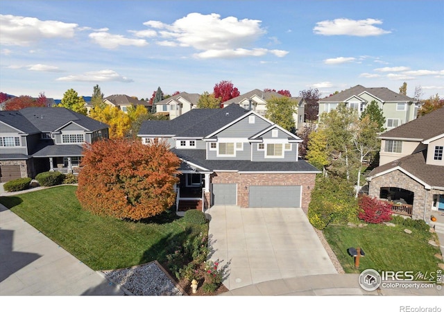 view of front of house with brick siding, a residential view, a front yard, a garage, and driveway