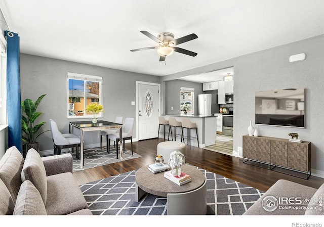 living room with baseboards, wood finished floors, and a ceiling fan