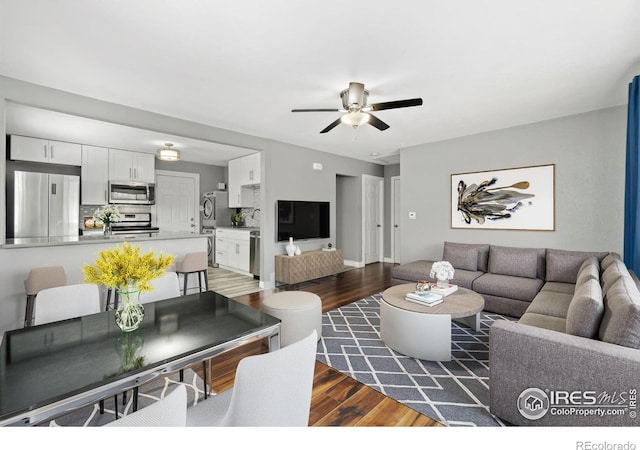 living area with a ceiling fan, wood finished floors, and baseboards