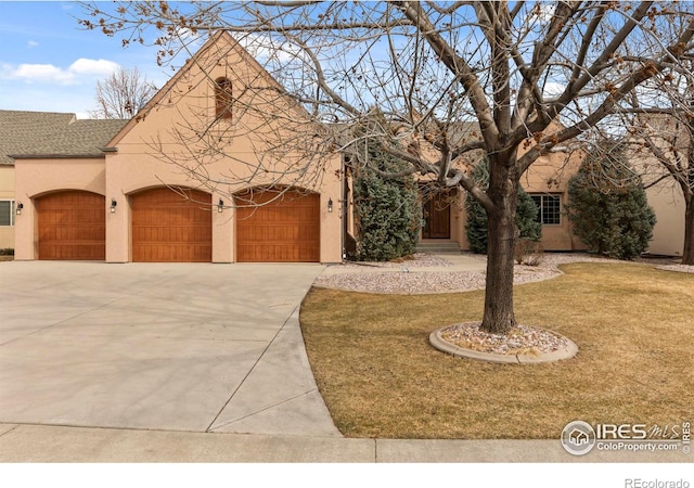 view of front of house with a front yard, roof with shingles, driveway, an attached garage, and stucco siding