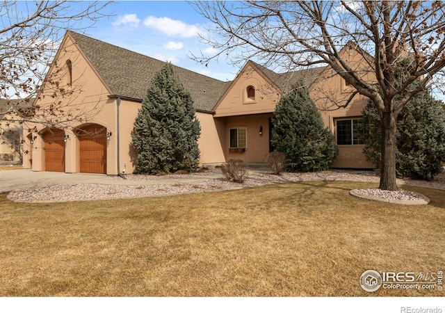 view of front of house with a garage, a shingled roof, a front yard, and stucco siding