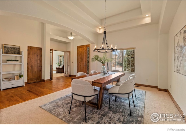 carpeted dining room featuring a high ceiling, a notable chandelier, baseboards, and arched walkways