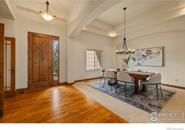 entryway with baseboards, a towering ceiling, wood finished floors, arched walkways, and a notable chandelier