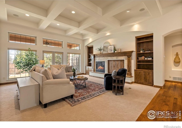 living area featuring a wealth of natural light, visible vents, coffered ceiling, and a tiled fireplace