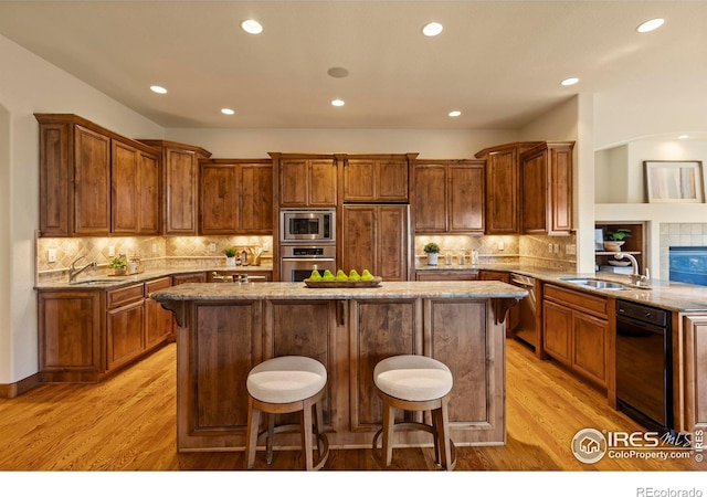 kitchen with built in appliances, light wood-style flooring, a center island, and a sink