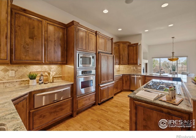 kitchen with light wood-style flooring, stainless steel appliances, a warming drawer, and brown cabinets