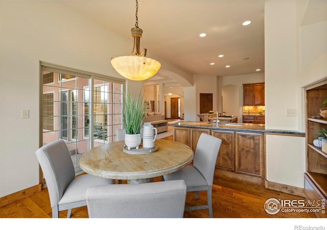 dining space featuring recessed lighting, baseboards, arched walkways, and wood finished floors