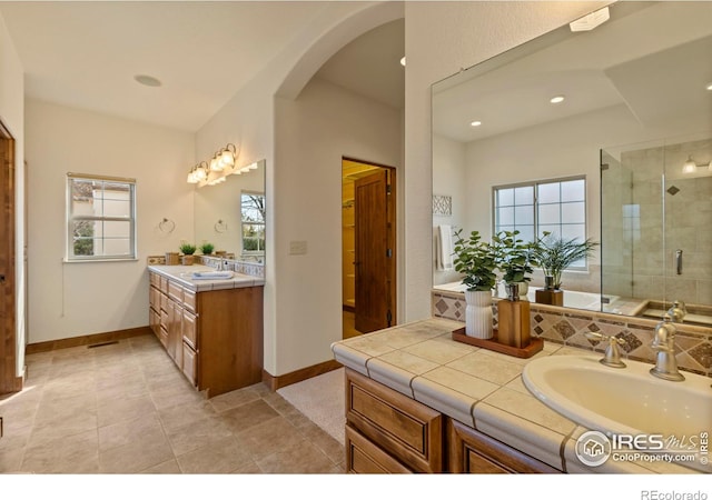 bathroom with baseboards, a healthy amount of sunlight, a stall shower, and vanity