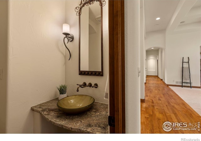 bathroom featuring recessed lighting, wood finished floors, and a sink