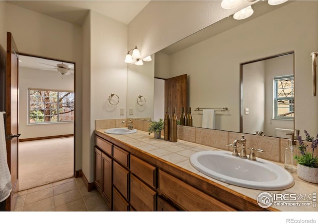 bathroom featuring tile patterned flooring, double vanity, baseboards, and a sink