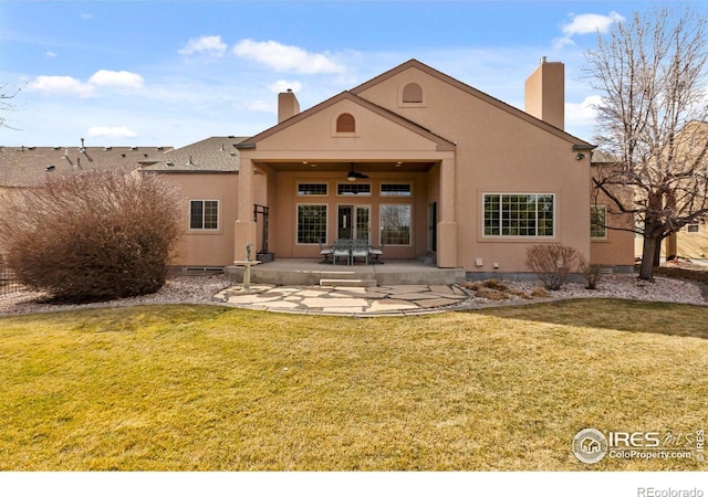 back of property featuring a yard, ceiling fan, stucco siding, a chimney, and a patio area