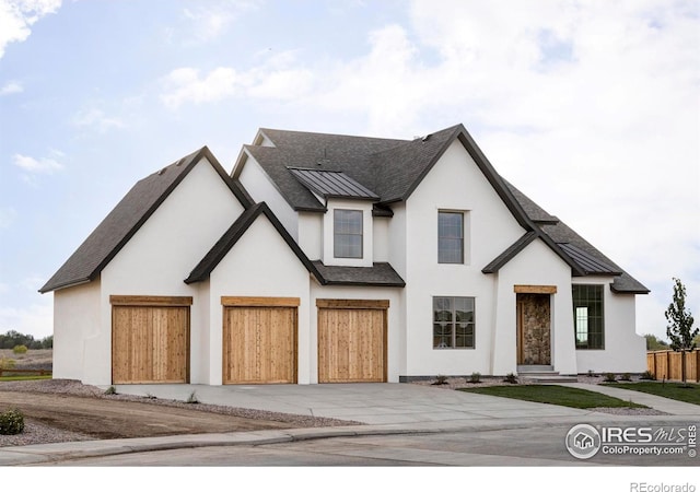 modern farmhouse with a standing seam roof, a shingled roof, concrete driveway, a garage, and metal roof