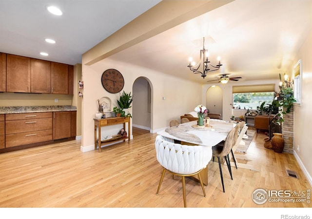 dining area featuring beamed ceiling, recessed lighting, arched walkways, light wood-style floors, and baseboards