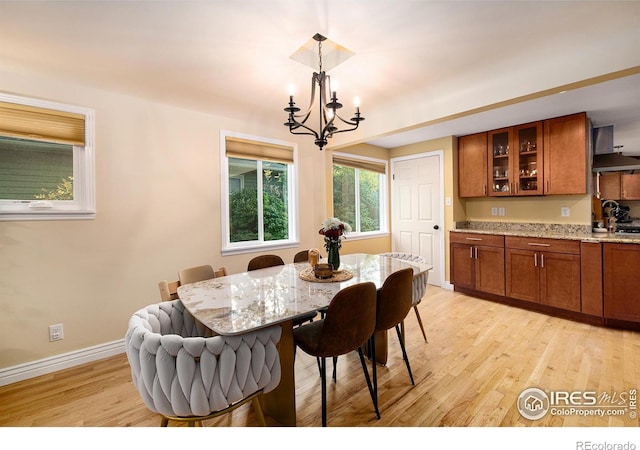 dining room featuring light wood finished floors, baseboards, and an inviting chandelier